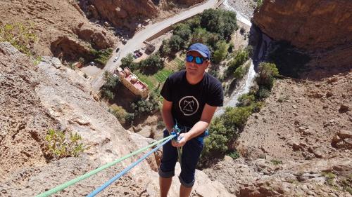 a man is standing on a rope in a canyon at Hotel De La Vallée in Aït Baha