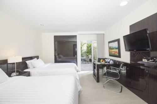 a hotel room with two beds and a television at GHL Hotel Portón Medellín in Medellín