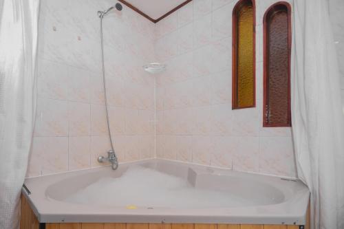 a bath tub with a shower and two windows at Pao Pao Lodge Algarrobo in Algarrobo
