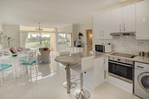 a kitchen with white cabinets and a table in it at L`Azur : Elegant Apartment with Sea View in Wilderness