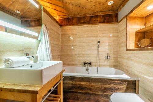 La salle de bains est pourvue d'un lavabo blanc et d'une baignoire. dans l'établissement Ferme de Margot Morzine - by EMERALD STAY, à Morzine