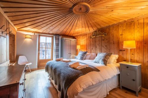 une chambre avec un grand lit avec un plafond en bois dans l'établissement Ferme de Margot Morzine - by EMERALD STAY, à Morzine