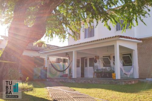 a white house with a tree in front of it at Tubiba Hostel in Tamandaré