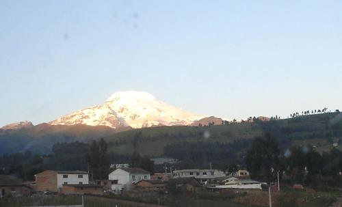a snow covered mountain on top of a city at Hospedaje San Fernando in Cayambe