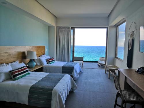a hotel room with two beds and a view of the ocean at Hotel Basalto in Punta Mita