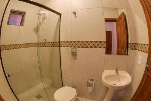 a bathroom with a shower and a toilet and a sink at Pousada Villa Prainha in Farol de Santa Marta
