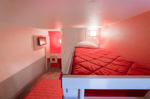 a small bedroom with a red bed in a room at Premiere Classe St Quentin in Saint-Quentin