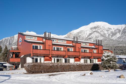 duży czerwony budynek przed górą w obiekcie Rocky Mountain Ski Lodge w mieście Canmore