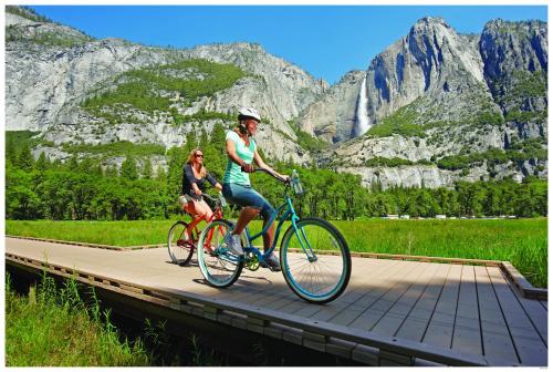 two people riding bikes on a boardwalk in the mountains at Yosemite Valley Lodge in Yosemite Village