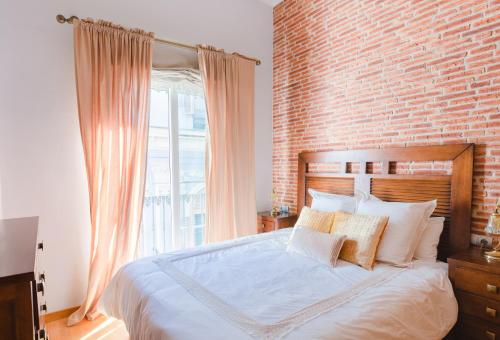 マラガにあるCorazón de Málagaのレンガの壁とベッド(枕付)が備わるベッドルーム1室が備わります。