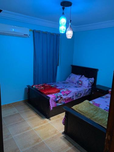 two beds in a room with blue lights at mody appartment at alexandria in Alexandria