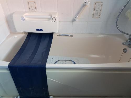 CEAD MILE FAILTE WEST BELFAST في بلفاست: حوض استحمام أبيض مع خط أزرق في الحمام