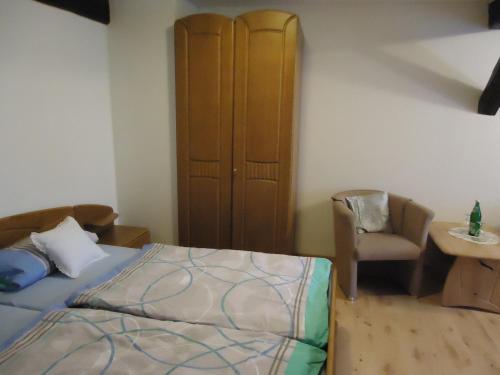 a bedroom with a bed and a chair and a cabinet at Pension an der Stadtmauer in Wernigerode