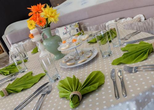 a table with a white table cloth with flowers and silverware at Hotel Nove in Svishtov