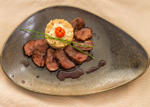 a plate of food with meat and a muffin at Hotel Nove in Svishtov