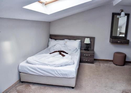a bedroom with a bed with white sheets and a mirror at Hotel Nove in Svishtov