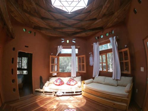 een woonkamer met een bank en 2 ramen bij Flor de Vida Geocabañas - Casa Gala in La Esmeralda