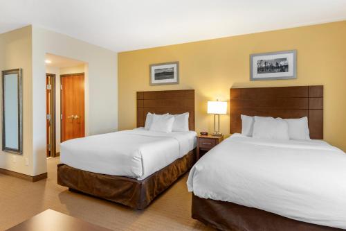 a hotel room with two beds with white sheets at MainStay Suites Near Denver Downtown in Denver