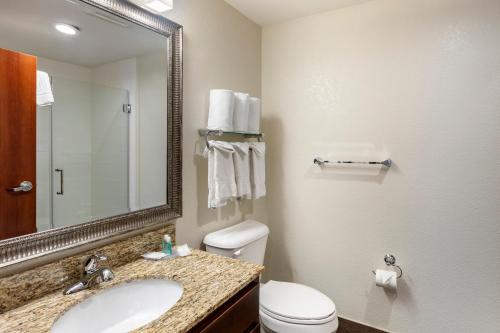 a bathroom with a sink and a toilet and a mirror at MainStay Suites Near Denver Downtown in Denver