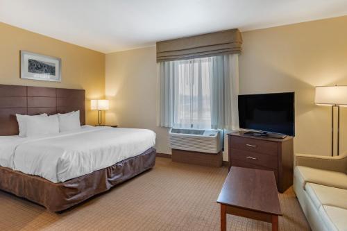 a hotel room with a bed and a flat screen tv at MainStay Suites Near Denver Downtown in Denver