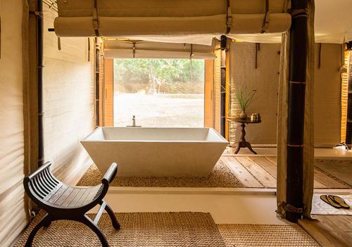 a bath tub in a room with a chair at The Beige in Siem Reap