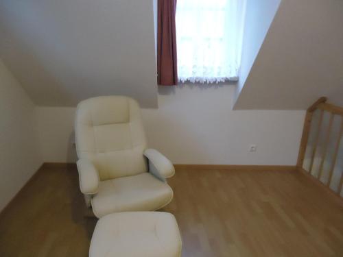 a living room with a chair and a stool at Pension an der Stadtmauer Apartments in Wernigerode