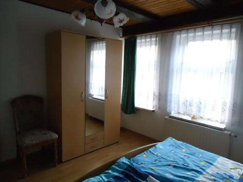 a bedroom with a bed and a chair and windows at Pension an der Stadtmauer Apartments in Wernigerode