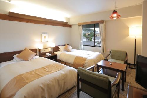 a hotel room with two beds and a desk at Kurashiki Kokusai Hotel in Kurashiki