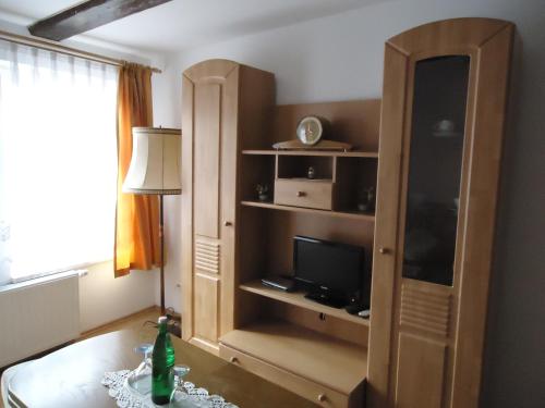 a living room with a tv and a cabinet at Pension an der Stadtmauer Apartments in Wernigerode