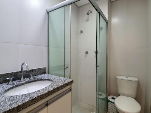 W łazience znajduje się umywalka i przeszklony prysznic. w obiekcie Flats Capitania Varam Pitangueiras w mieście Guarujá