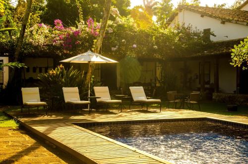 a patio with chairs and an umbrella next to a pool at Pousada da Marquesa in Paraty