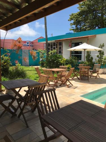 a patio with a table and chairs and a pool at Santa Cecília Pousada in Guarujá