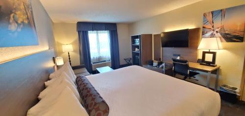 a hotel room with a large white bed and a desk at Best Western Plus Hollywood/Aventura in Hollywood