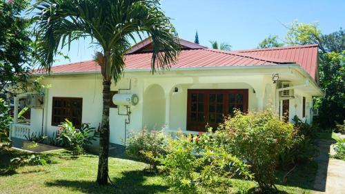 a small house with a palm tree in front of it at Ogumka, Self catering , Beoliere, Mahe in Victoria