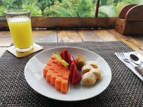 un plato de fruta en una mesa con un vaso de zumo de naranja en Finca Jardín del Agua, en Sasaima