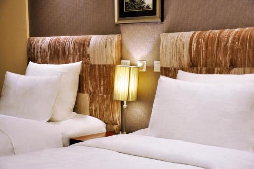 a hotel room with two beds and a lamp at Pullman Beijing South in Daxing