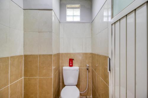 a bathroom with a toilet with a red bottle on it at RedDoorz near Condongcatur Bus Station in Yogyakarta
