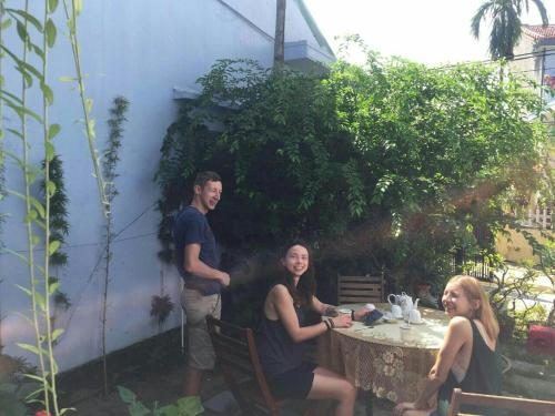a group of people sitting around a table in a yard at Cherry Garden Homestay in Hoi An