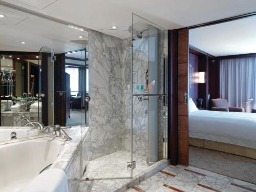 een badkamer met een bad en een douche en een bed bij Grand Hyatt Shanghai in Shanghai