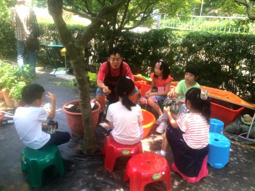 a group of children sitting onools under a tree at Rainbow Bridge B&B in Sanzhi