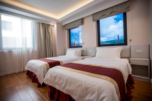 two beds in a hotel room with two windows at Hotel Americano in Garapan
