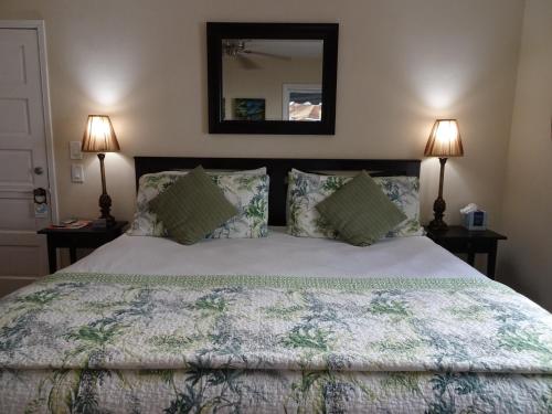 a bedroom with a bed with two lamps and a mirror at Suite Dreams Inn by the Beach in Key West