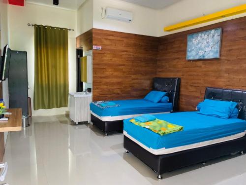 two beds in a room with blue sheets at Nuwono Tasya Syariah in Bandar Lampung