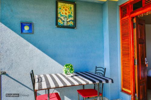 una mesa y sillas en una habitación con una pared azul en Will Guest Homestay, en Ella