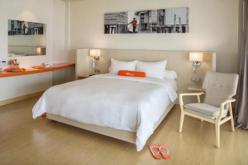 a bedroom with a large white bed and a chair at HARRIS Resort Barelang Batam in Sagulung