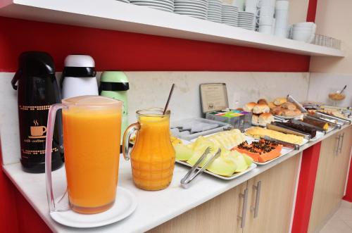 a kitchen counter with two glasses of orange juice and food at Pousada Mar Do Leste in Florianópolis