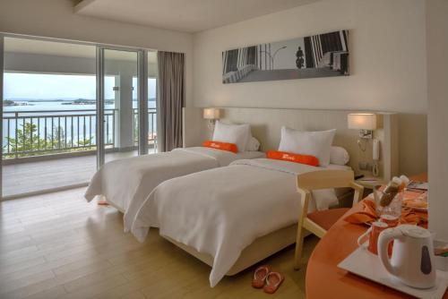 two beds in a hotel room with a balcony at HARRIS Resort Barelang Batam in Sagulung