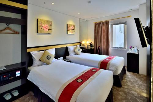 a hotel room with two beds and a television at Gino Feruci Kebon Jati by KAGUM Hotels in Bandung