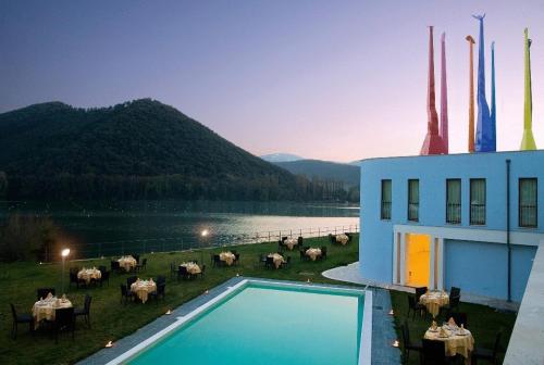 a building with a swimming pool next to a body of water at Hotel Miralago in Piediluco