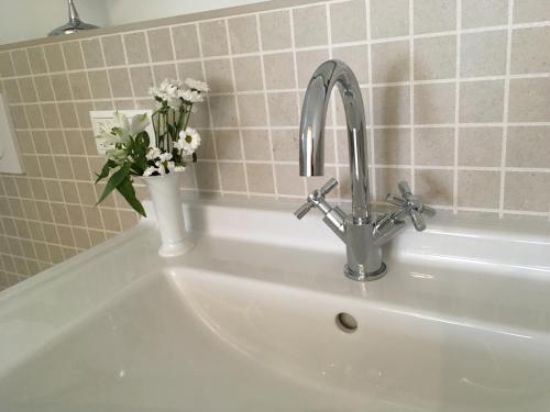 a white sink with a vase of flowers on it at Großzügiges Appartement -ruhig und doch zentral in Odenthal
